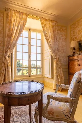 Chambre Jaune: upholstered armchair and gallery-edged guéridon by a sunlit window
