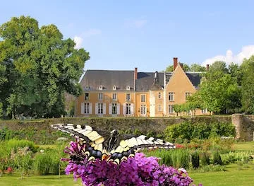 Swallowtail butterfly on purple blossoms in the garden, the château façade behind