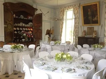Grande Salle à Manger set for a wedding: round tables, white-draped chairs, white bouquets and the porcelain dresser